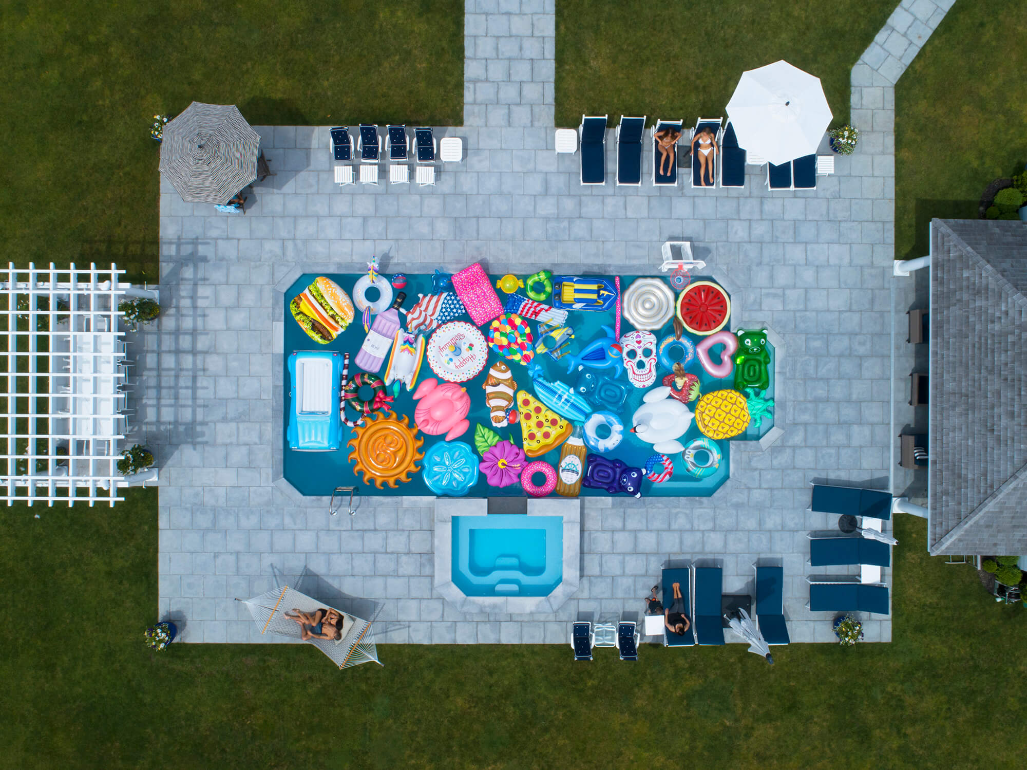 Top-down view of a pool party with pool toys and people around the pool.