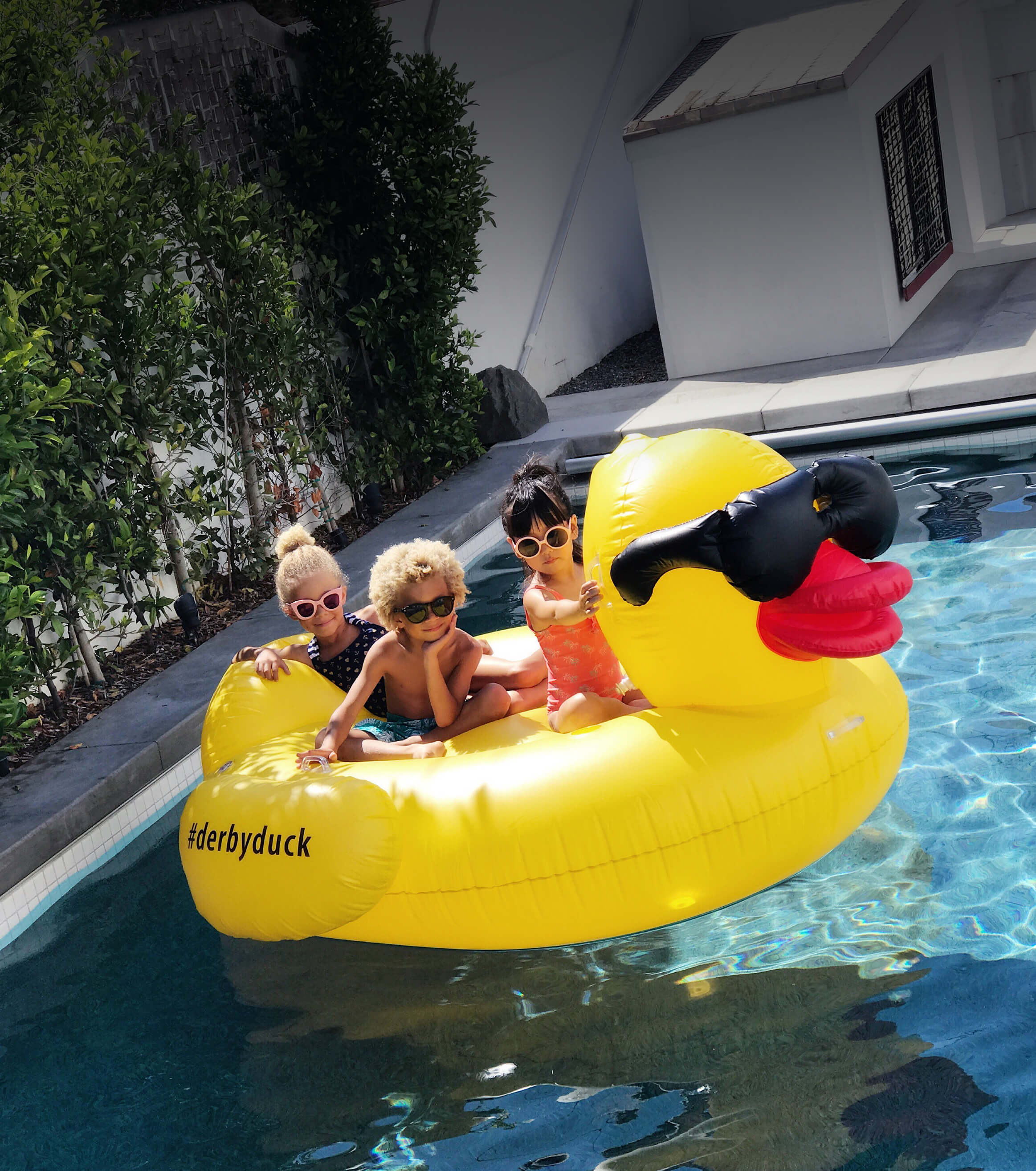Children on a yellow rubber duck inflatable raft in a pool